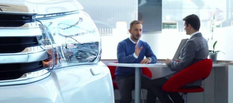 Buyer and salesperson sitting at the table in the car showroom