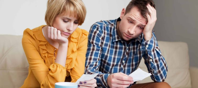 Sad, depressed young couple paying bills.
