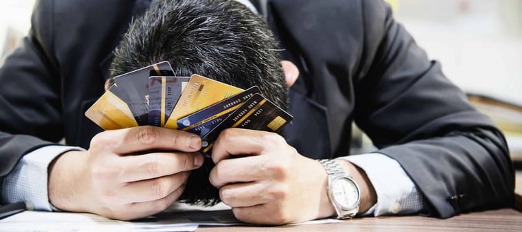 Businessman holding credit cards thinking seriously about payment loan problem - people with personal financial crisis concept