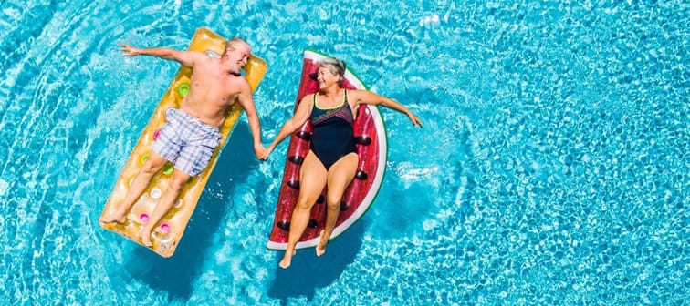 Senior couple on floating rafts in a swimming pool