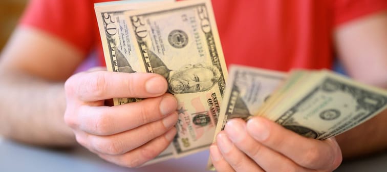 Man wearing red shirt counts out money