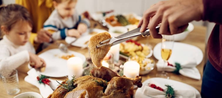 A turkey is carved at a family Thanksgiving table.