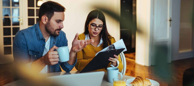 Young couple looking through paperwork over breakfast