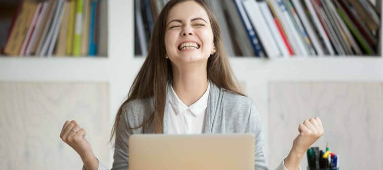 Excited female student feels euphoric celebrating online shopping