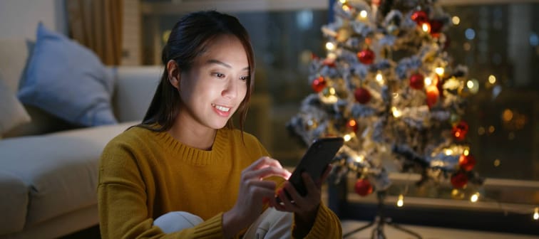 Woman on phone beside Christmas tree