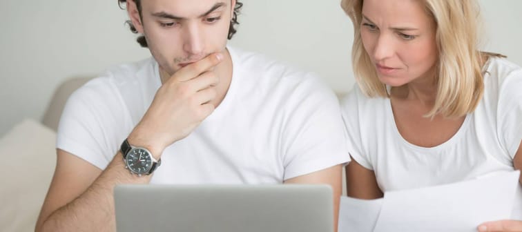 Young man and woman working with laptop, holding documents