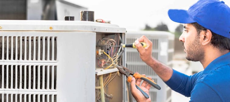 a contractor works on an air conditioning system with tools
