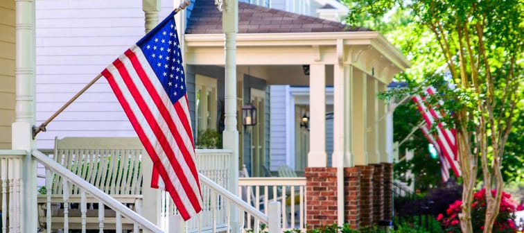 A line of suburban homes display large American Flags
