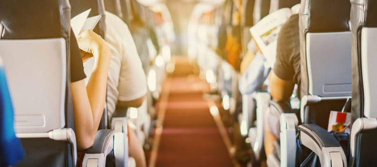 passenger seat, Interior of airplane with passengers sitting on seats and stewardess walking the aisle in background. Travel concept,vintage color,selective focus