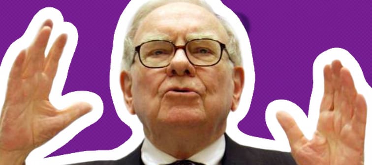 Warren Buffett speaks at podium with his hands in the air