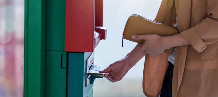 Closeup woman holding the wallet and withdrawing the cash via ATM