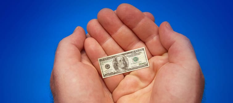 hands holding last small banknote of US dollar, blue background