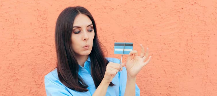 Woman Cutting Credit Card in Half with Scissors. Millennial girl having financial problems for spending too much money