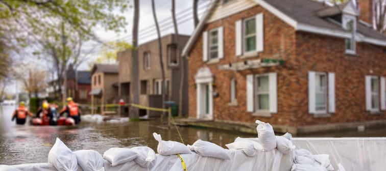 Flood Protection Sandbags with flooded homes in the background.
