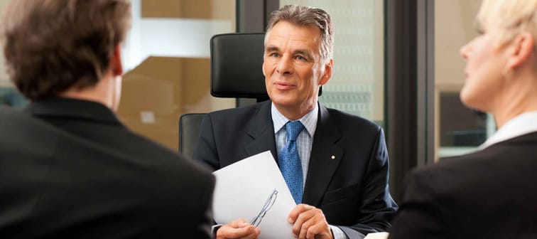 Mature lawyer or notary with clients in his office in a meeting