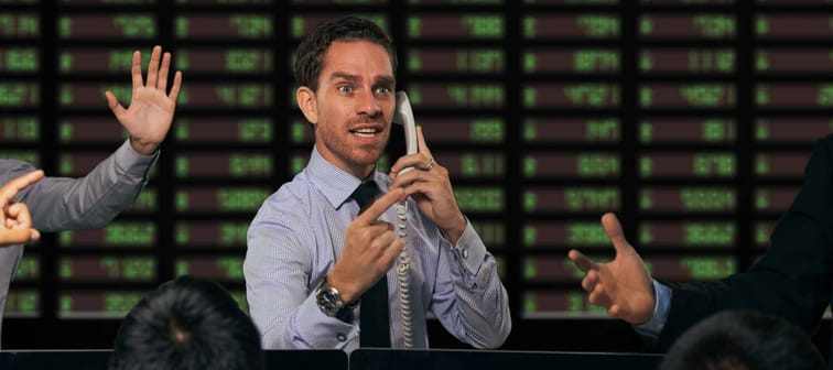 Trader gesturing at stock exchange
