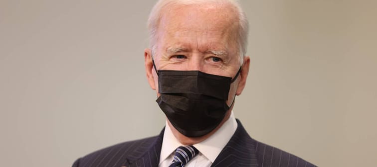 Joe Biden wears a face mask, smiling under it and clapping his hands
