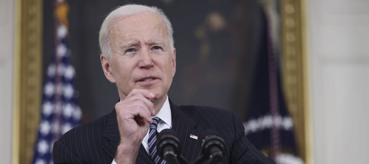 President Joe Biden speaks at a podium with his hand up, making a gesture