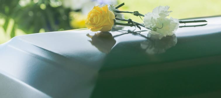 A closeup of flowers atop a funeral casket outdoors.