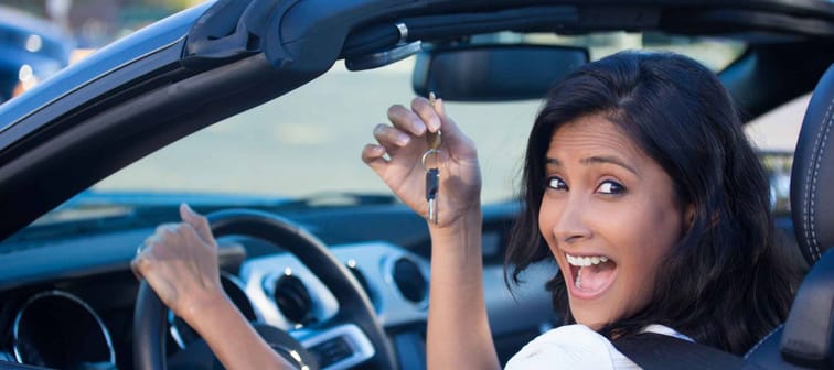Closeup portrait, young cheerful, joyful, smiling, woman holding up keys to her first new sports car.
