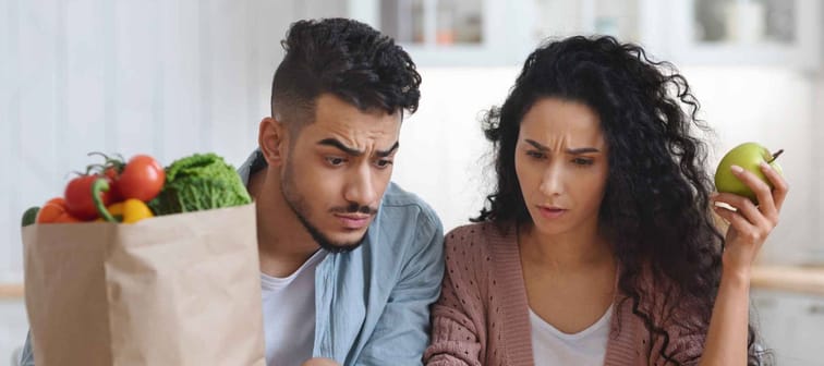 Frustrated Arab Spouses In Kitchen Checking Bills After Grocery Shopping,