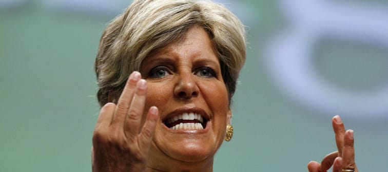 Suze Orman holds her hands up and makes an aggressive face