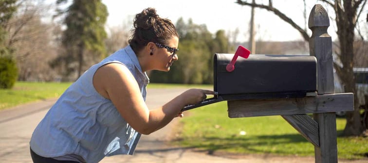 Attractive woman looks inside a mailbox.