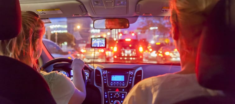 Two women in front of a car, view of the city and traffic through the windshield