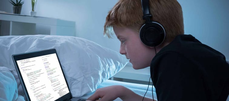 Boy Listening To Music Programming On Laptop