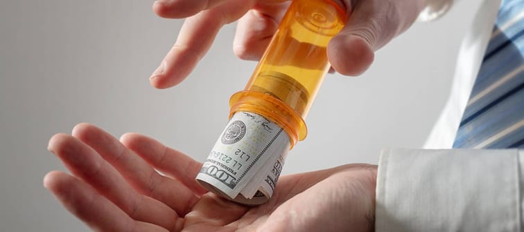 Doctor pouring money out of a pill bottle