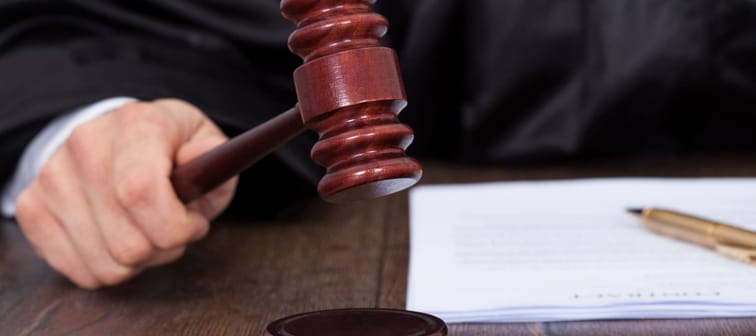 Cropped image of judge giving verdict by hitting mallet at desk