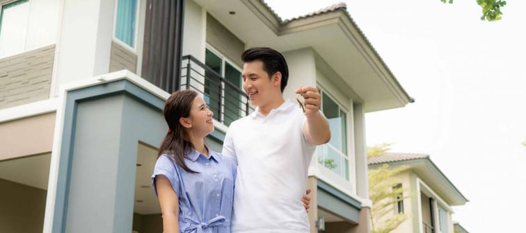 Portrait of young couple looking happy in front of their new house