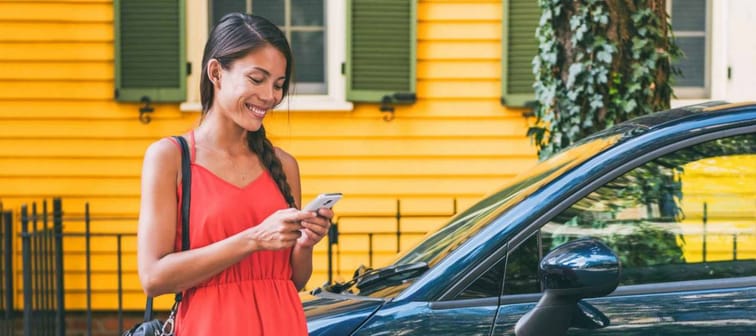 Car sharing mobile phone tech lifestyle. Ridesharing app Asian woman using cellphone for travel vacation.