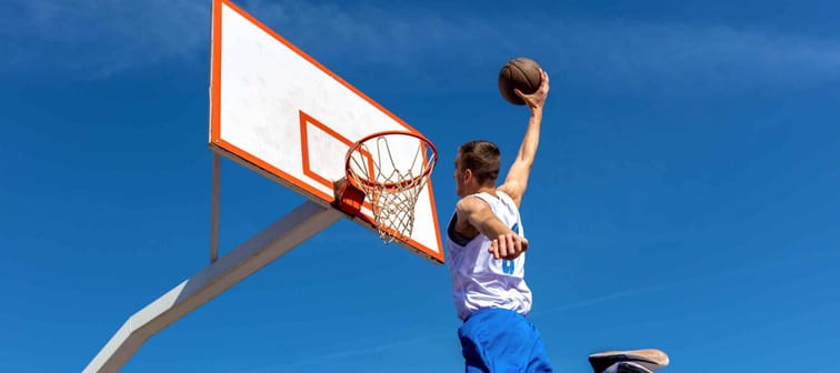 Young Basketball street player making slam dunk
