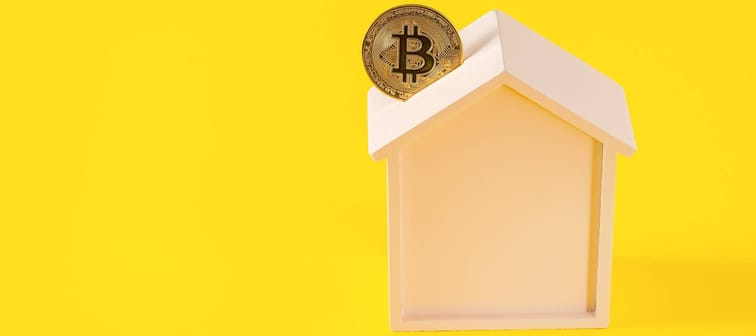 Bitcoin being placed in house-shaped piggybank