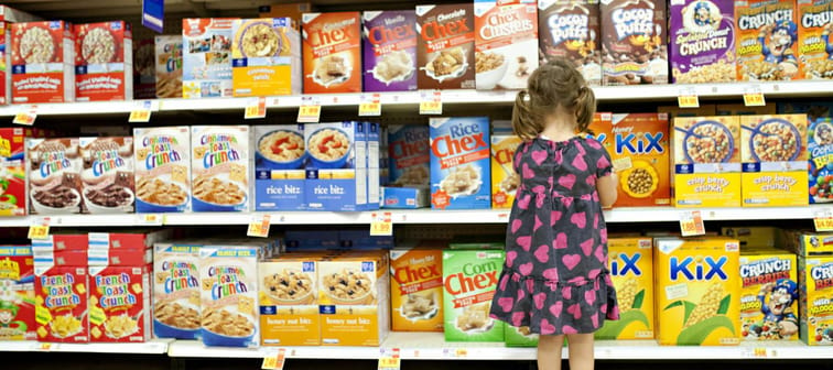 little girl picking out a cereal at the store