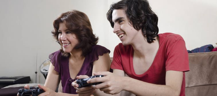 Mother and young adult son playing video games.