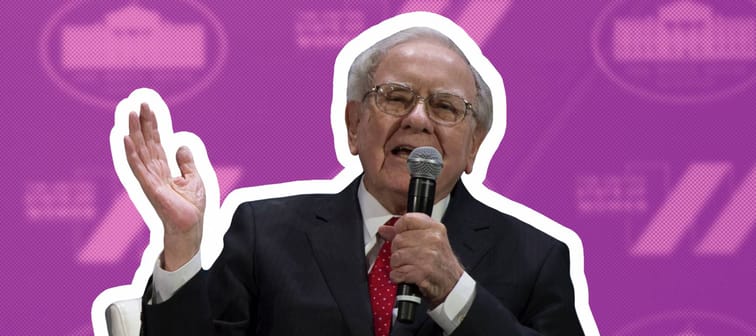 Warren Buffett sits on a stage and talks into a microphone.