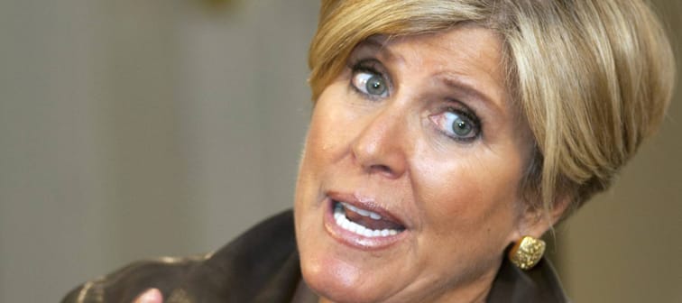 Suze Orman tilts head and holds up hands while talking.