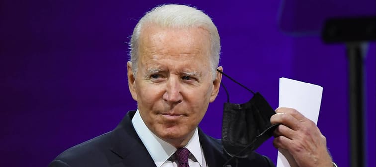U.S. President Joe Biden removing his mask and pointing to a piece of paper in his hand