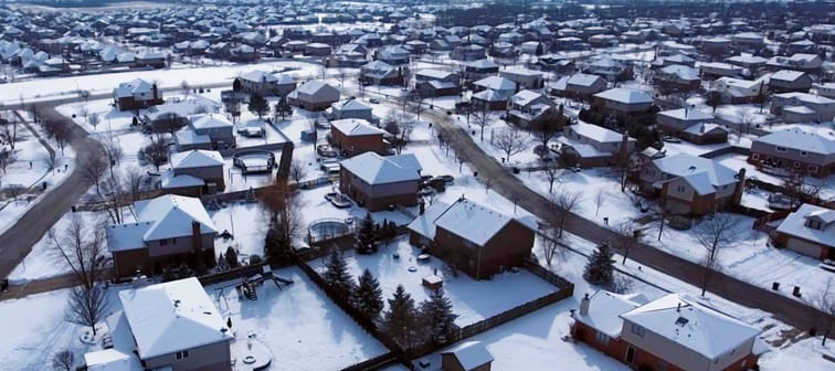 Overhead aerial view of residential houses and yards along suburban street covered in snow - Travel and leisure concept