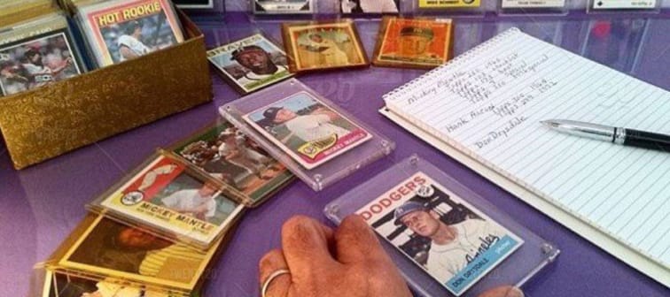 Hand at his home office desk admiring his baseball card collection and having fun playing.