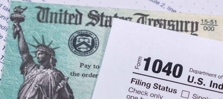 US Treasury stimulus check laying on a form 1040 tax return for 2020 to illustrate questions about qualification for payment