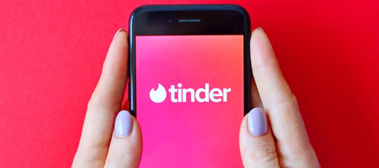 Illustrative editorial of Tinder logo on smartphone screen in female hands.