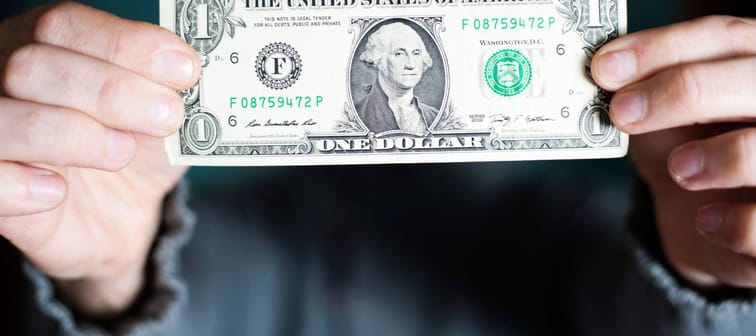 A man holds a U.S. 1 one dollar.
