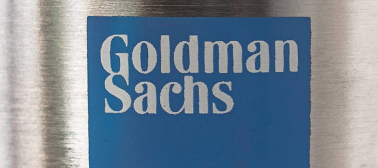 Light blue logo of Goldman Sachs on a metallic convex surface.