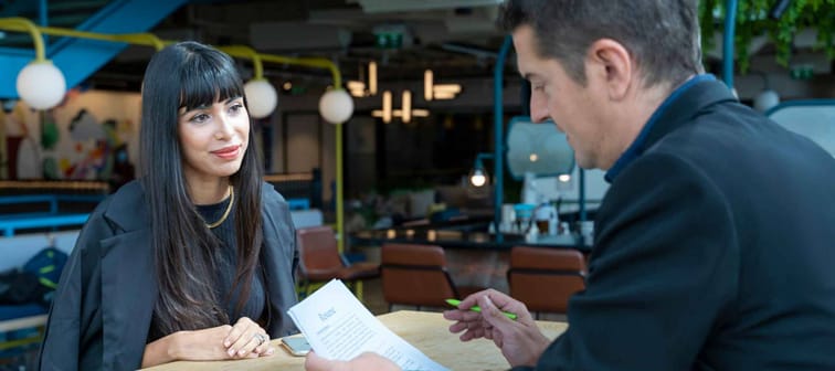 Human resource manager is interviewing young applicant while looking at her resume for work experience profile