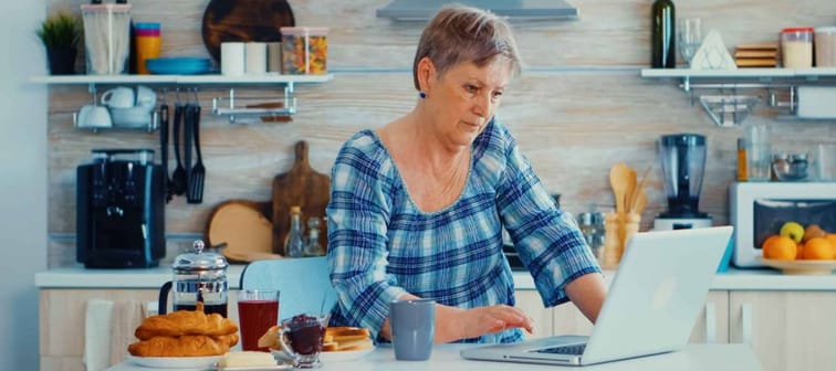 Elderly retired person working from home, telecommuting using remote internet job online communication on modern