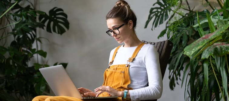 Focused millennial woman gardener watching educational webinar on laptop, remotely online work