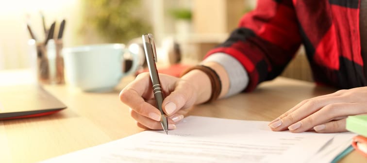 A closeup of a woman's hand signing a contract